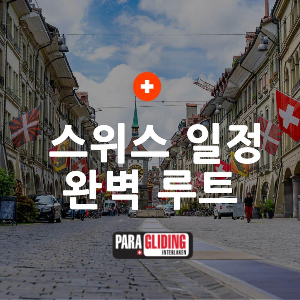 Rue bordée de drapeaux en ville suisse avec texte en coréen sur le parapente à Interlaken.