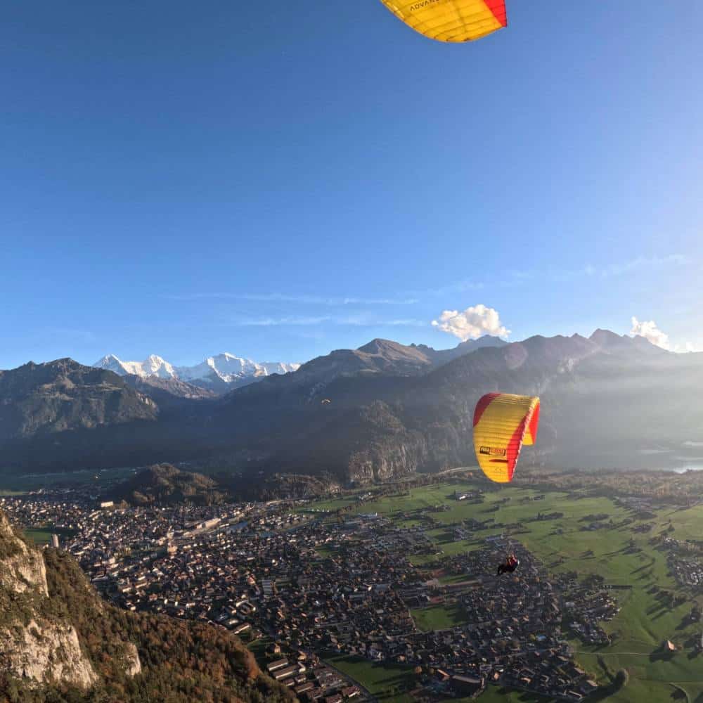 Vol en parapente au-dessus d'Interlaken avec vue sur les montagnes enneigées des Alpes suisses.