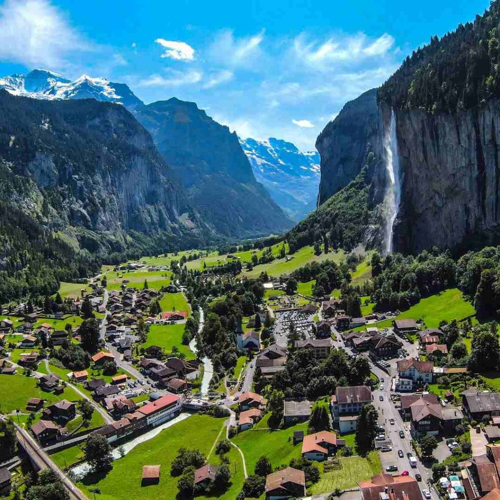 Village pittoresque suisse avec chute d'eau dramatique, montagnes majestueuses et maisons traditionnelles. Vue aérienne.